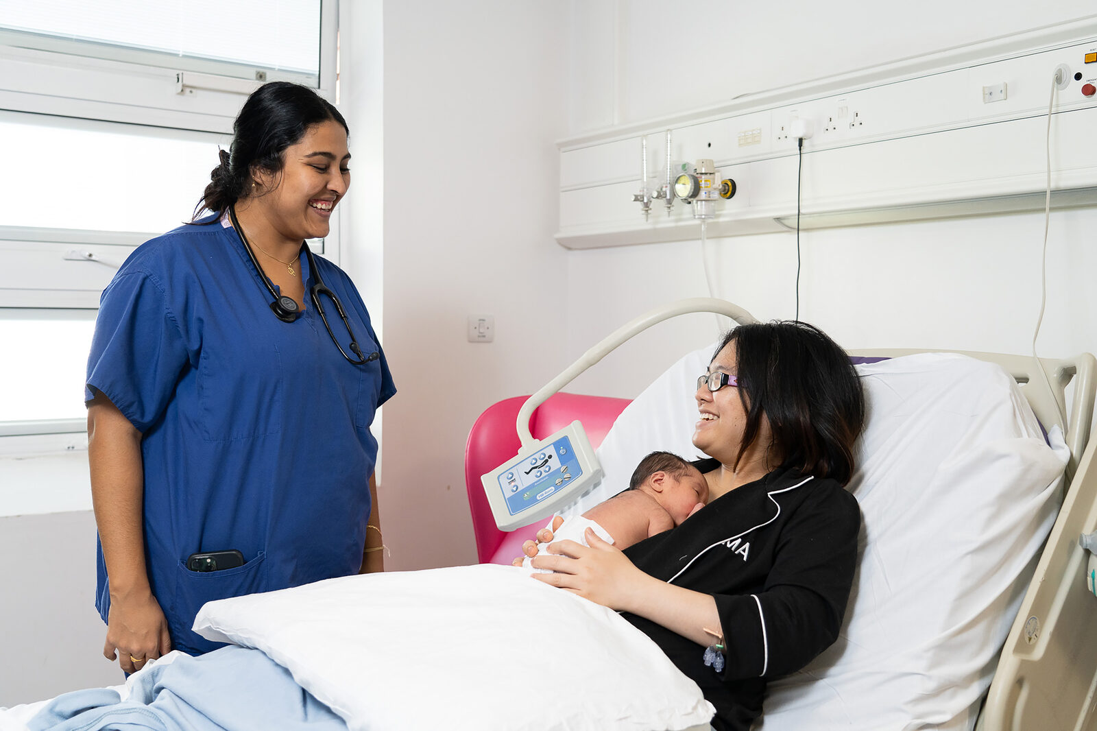 Midwife at the bedside talking with a new mother holding her baby